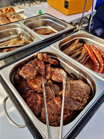 Grillbuffet mit Steaks und Würstchen im Freien.