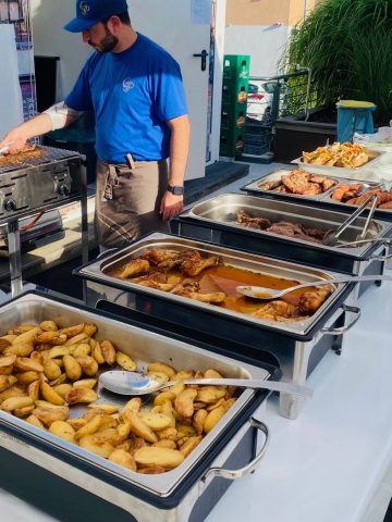 Mann bedient Grillstand mit verschiedenen Speisen.