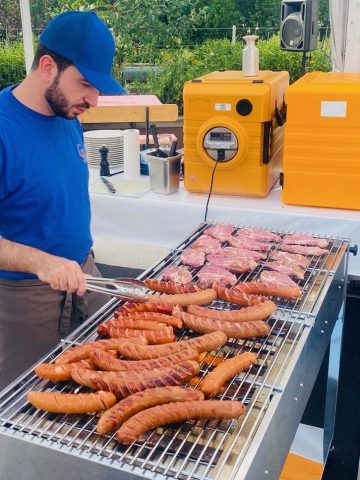 Mann grillt Würstchen und Steaks im Freien.