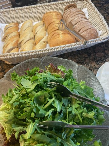 Frischer Salat und Brotkörbe auf Küchentheke.