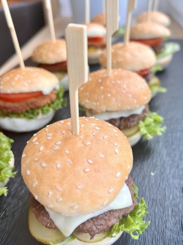 Mini-Burger mit Spießen auf Schieferplatte.