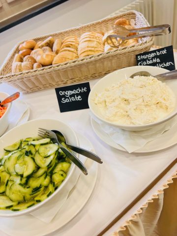 Frische Salate und Stangenbrot auf Buffet-Anrichte.